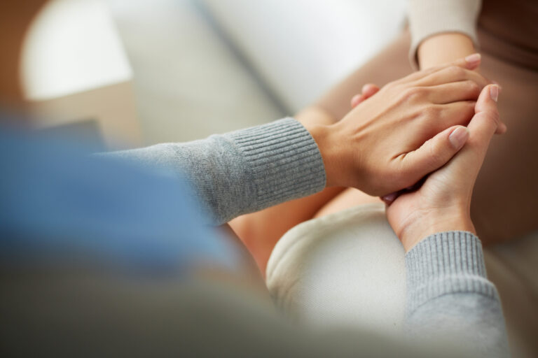 Close-up of hands clasped together in comfort